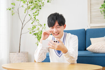 リビングでスマートフォンで動画を見る男子高校生