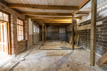 Abandoned building interior in disrepair with debris, exposed pipes, and missing doors awaiting...