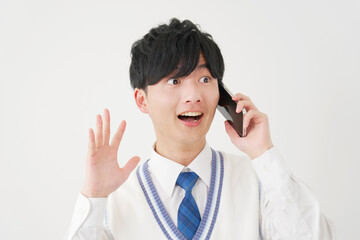 スマートフォンで電話しながら驚く男子高校生　白背景