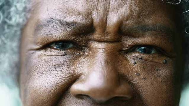 Serious Senior African American woman eyes frowning, macro tight closeup of a black lady looking at camera, 80s wrinkled person