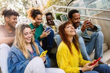 Young group of happy people using mobile phone relaxing together outdoors. Smiling multiracial...