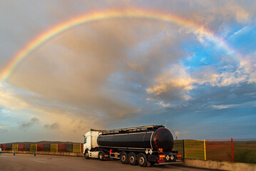 Tanker truck with dangerous goods parked under a spectacular sky with rainbow.