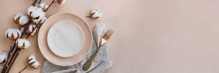 Foto op Canvas Panorama. Modern minimal table place setting neutral peach fuzz color top view decorated with flowers cotton branch. Space for text or menu. Scandinavian style tableware. © juanorihuela