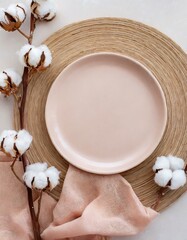 Fototapeta na wymiar Modern minimal table place setting neutral peach fuzz color top view decorated with flowers cotton branch. Space for text or menu. Scandinavian style tableware.