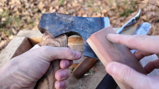 Close-up of sharpening an carving axe by using whetstone before wood carving. Carving equipments on the stand.