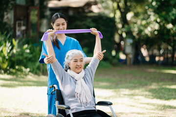 Asian physiotherapist helping elderly woman patient stretching arm during exercise correct with...