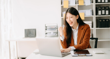 Asian business woman are delighted and happy with the work they do on their tablet, laptop and taking notes at the office..