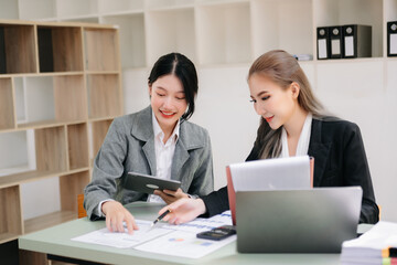 Two Asian businesswoman and man discuss investment project working and planning strategy with tablet laptop computer in office..