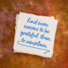 find more reasons to be grateful than to complain - inspirational handwriting on art paper, positivity and  personal development concept