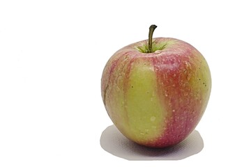 Fresh yellow and red whole apple with some drops of water on surface, placed on porous surface, white background. 