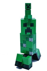 Fototapeta premium LEGO Minecraft small and big figure of explosive green mob called Creeper, small one sitting on head of big one. 