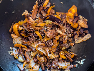 Vegan stir fry consisting of cabbage, pepper and seitan, in wok