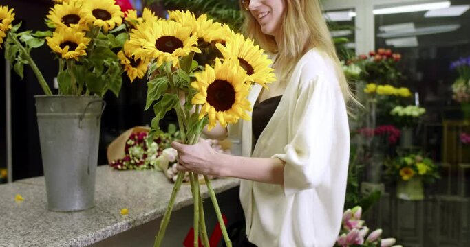 A florist at a flower store assembles a bouquet of sunflowers