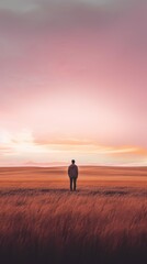 Fototapeta na wymiar Lone Man Standing in Field at Sunset