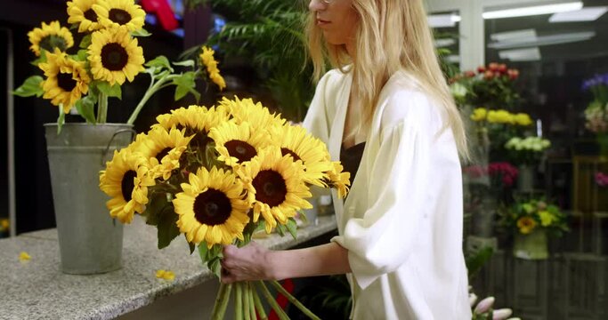 A florist at a flower store assembles a bouquet of sunflowers