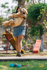 Woman carrying in arms a puppy dog in a park