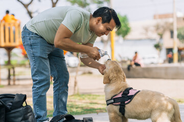 Man pouring water on a puppy dog on a park