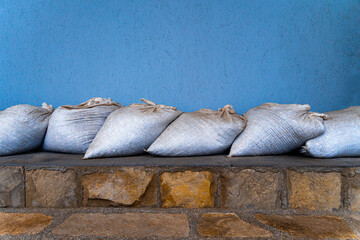 sandbags lie on the rocks near the wall to protect from the flood on the seashore in winter in a storm - Powered by Adobe