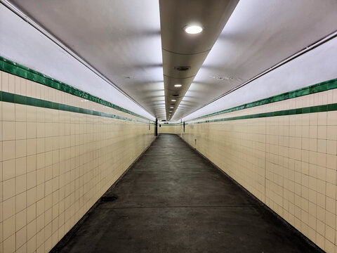 Underground Tunnel with Tiles Walls. Some overhead lights broken and not working. Green stripe tiles on the wall