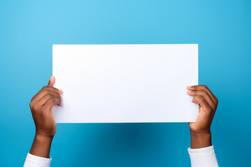 African american man holding blank sheet of paper on blue background