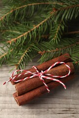 Cinnamon sticks and fir branches on wooden table, closeup