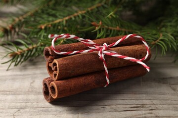 Cinnamon sticks and fir branches on wooden table, closeup