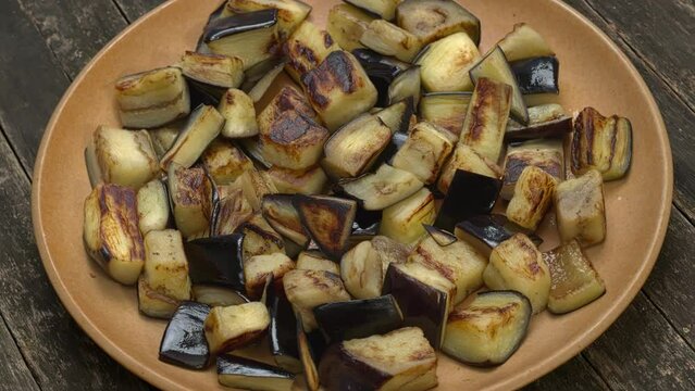 Sauteed aubergine chunks on a plate. Table spin.