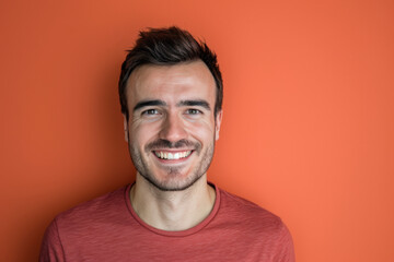 Obraz premium A man in a red shirt is smiling in front of an orange wall