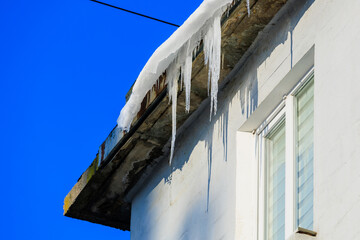 Large icicles on the roof pose a danger to passersby. Background with selective focus and copy space