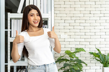 Young woman joyfully poses with hands thumb up and a happy expression