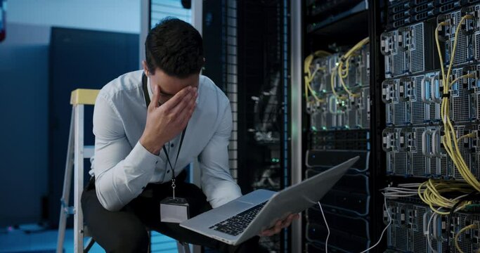 Man, working and headache from programming with data on pc in server room or technician with burnout. IT, programmer and person tired from fatigue and fix mistake, error or fail in datacenter system