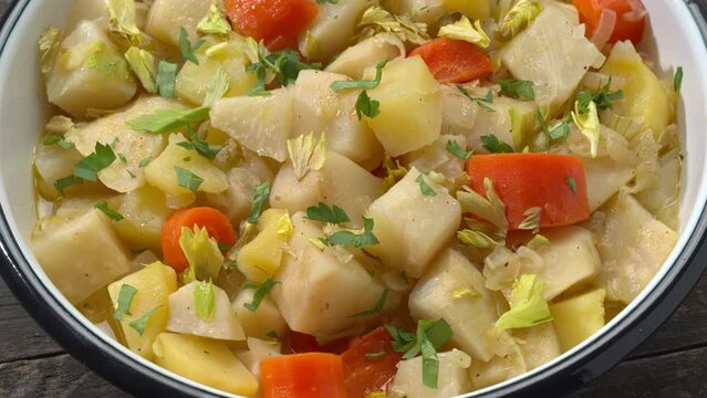 Turkish-style braised celeriac (Zeytinyağlı kereviz) in enameled bowl. Table spin.