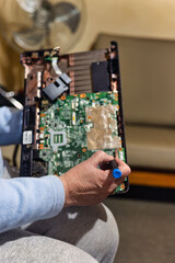 old woman with a laptop computer in her lap and screwdriver in her hand trying to repair it