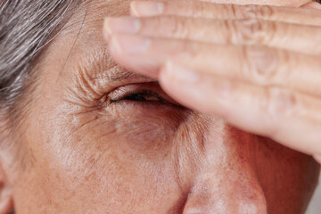 Close up of a mature woman squinting with hand on forehead