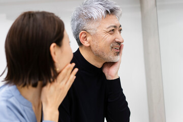 鏡の前でスキンケアをする夫婦
