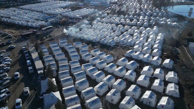 Elbistan,Kahramanmaras,Turkey - 18 Feb 2023: in the epicenter of the earthquake, numerous humanitarian shelters and humanitarian aid workers on the field. Smoke from heating stoves in the air. Aerial.