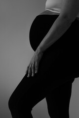 Maternal Glow: Black and White Silhouette of a Pregnant Woman. Side profile of a pregnant woman, showcasing the curve of her abdomen and legs. The monochromatic tones enhance this moment