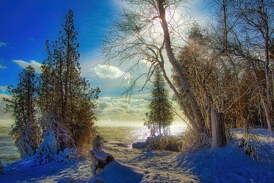 Sunny Winter day landscape of  the ice-coated Lake Michigan shoreline beside a forest covered in fresh snow at Cave Point in Door County, near Valmy, Wisconsin.