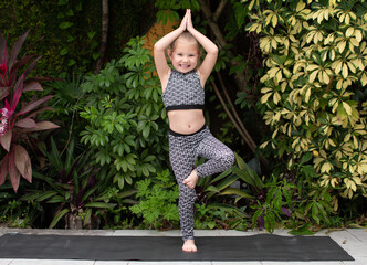 Little girl doing yoga tree pose. Preschooler practicing yoga