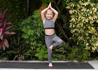 Foto op Plexiglas anti-reflex Little girl doing yoga tree pose. Preschooler practicing yoga © Ana