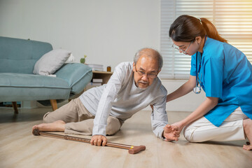 Disabled elderly old man patient with walking stick fall on floor and caring young assistant at...