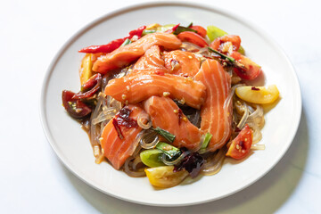 Spicy salad with fresh salmon and potato noodles mixed fermented fish sauce on white plate.