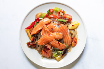 Spicy salad with fresh salmon and potato noodles mixed fermented fish sauce on white plate.