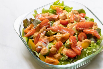 Fresh salmon with healthy green salad, avocado and cherry tomato in glass bowl. 