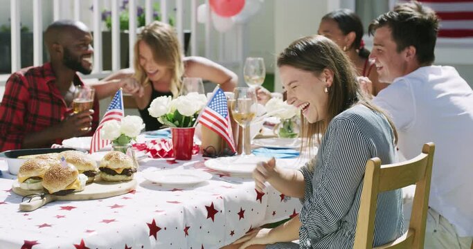Friends, laughing and party, American flag for celebration and eating with drinks at bbq outdoor. People, comedy on holiday and meal with diversity, social and reunion for fourth of July in USA