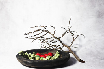 Green and red palm fruits (buah palem) on wooden plate.