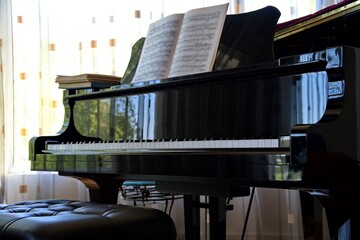 Closeup of black piano against the window