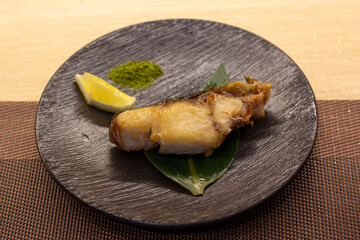 Buri Kama Shioyaki on black plate with copy space