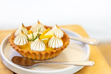 Lemon Tart in white plate on wooden table with copy space.