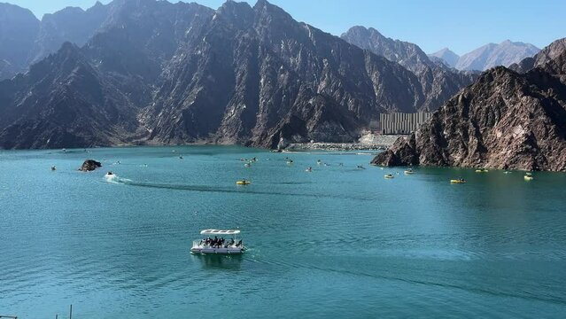 landscape view of Hatta dam lake and Hajar mountain in the Dubai, UAE. People enjoy weekends water adventure activities